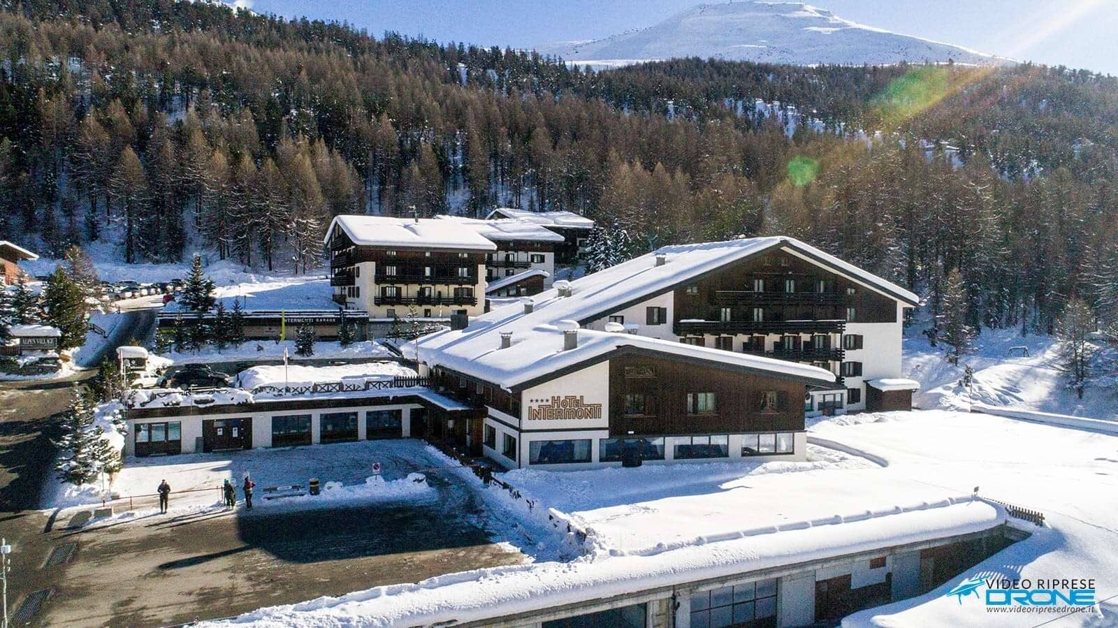 Aerial view of chalet complex with mountain backdrop and on-site parking
