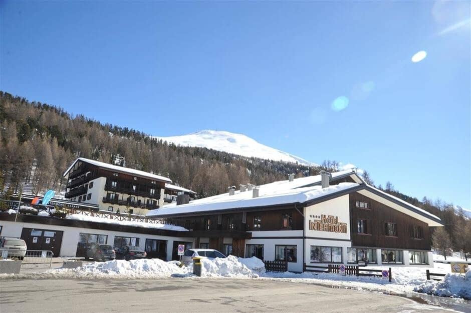 Hotel exterior with on-site parking and mountain backdrop near ski slopes