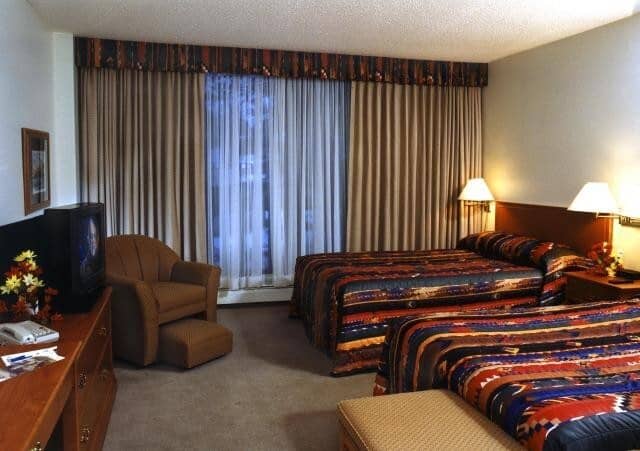 Bedroom with two queen beds and armchair with ottoman