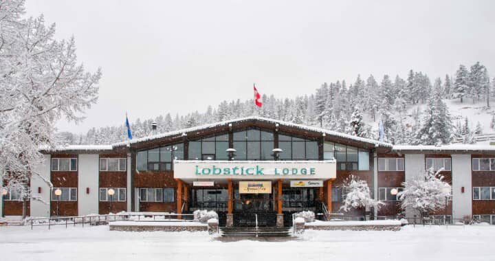 Lobstick Lodge exterior with floor-to-ceiling windows and snowy mountain backdrop