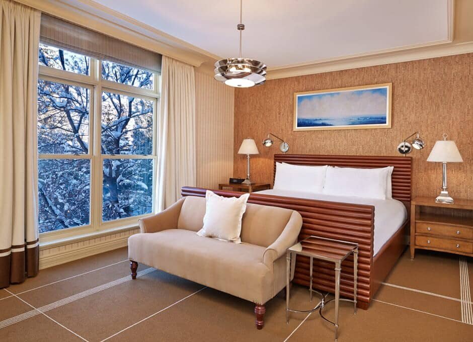 Primary bedroom with king bed, loveseat, and snowy forest view