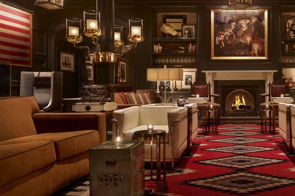 Lounge with wood-burning fireplace, library shelving, and armchair seating