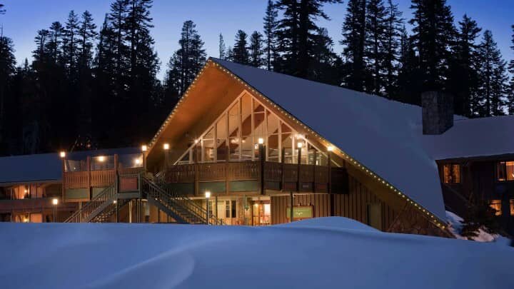 A-frame mountain lodge with floor-to-ceiling windows and wrap-around deck