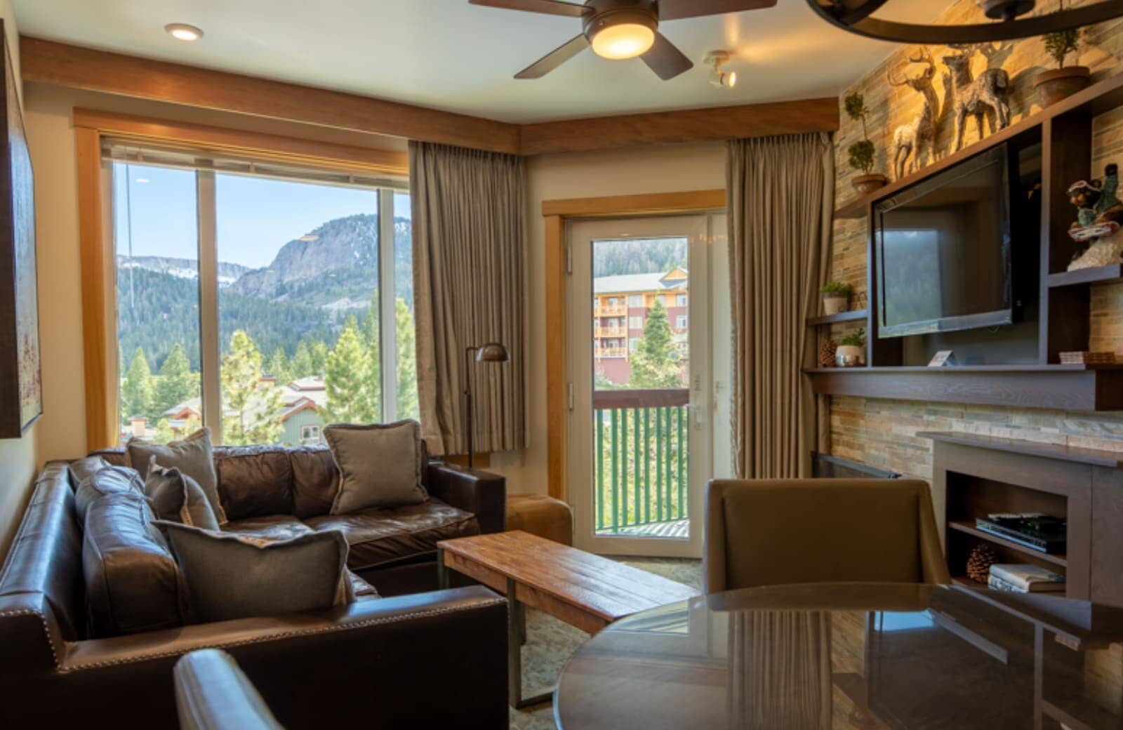 Living room with leather sectional, fireplace, and balcony with mountain views