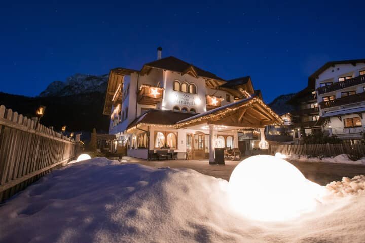 Chalet entrance at night with illuminated pathway and mountain backdrop
