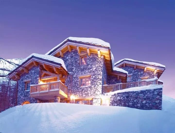 Stone and timber chalet with multiple private balconies and snow-covered grounds