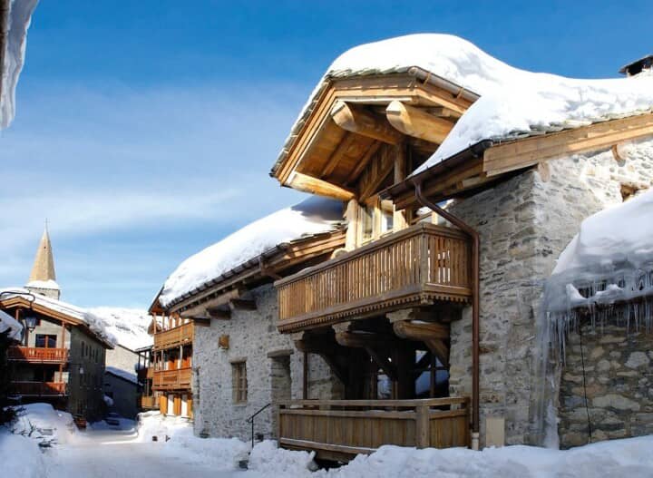 Stone chalet exterior with private wooden balconies and village center proximity