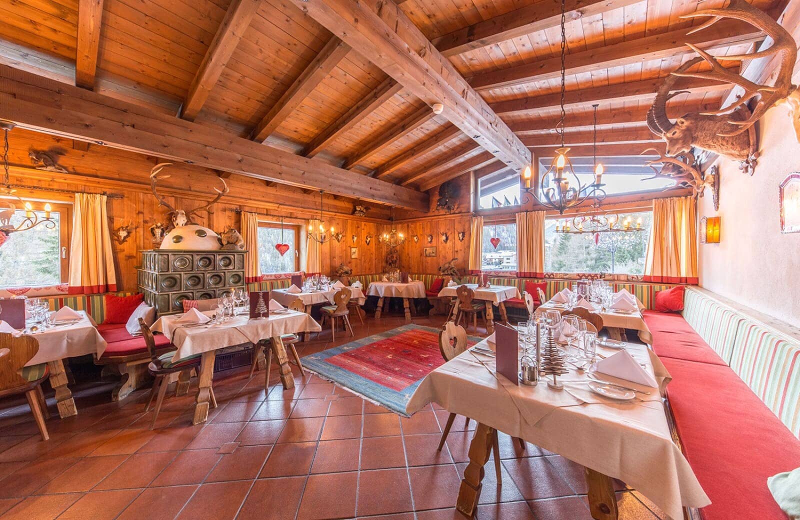 Dining area with wood-beamed ceilings and traditional tiled ceramic stove