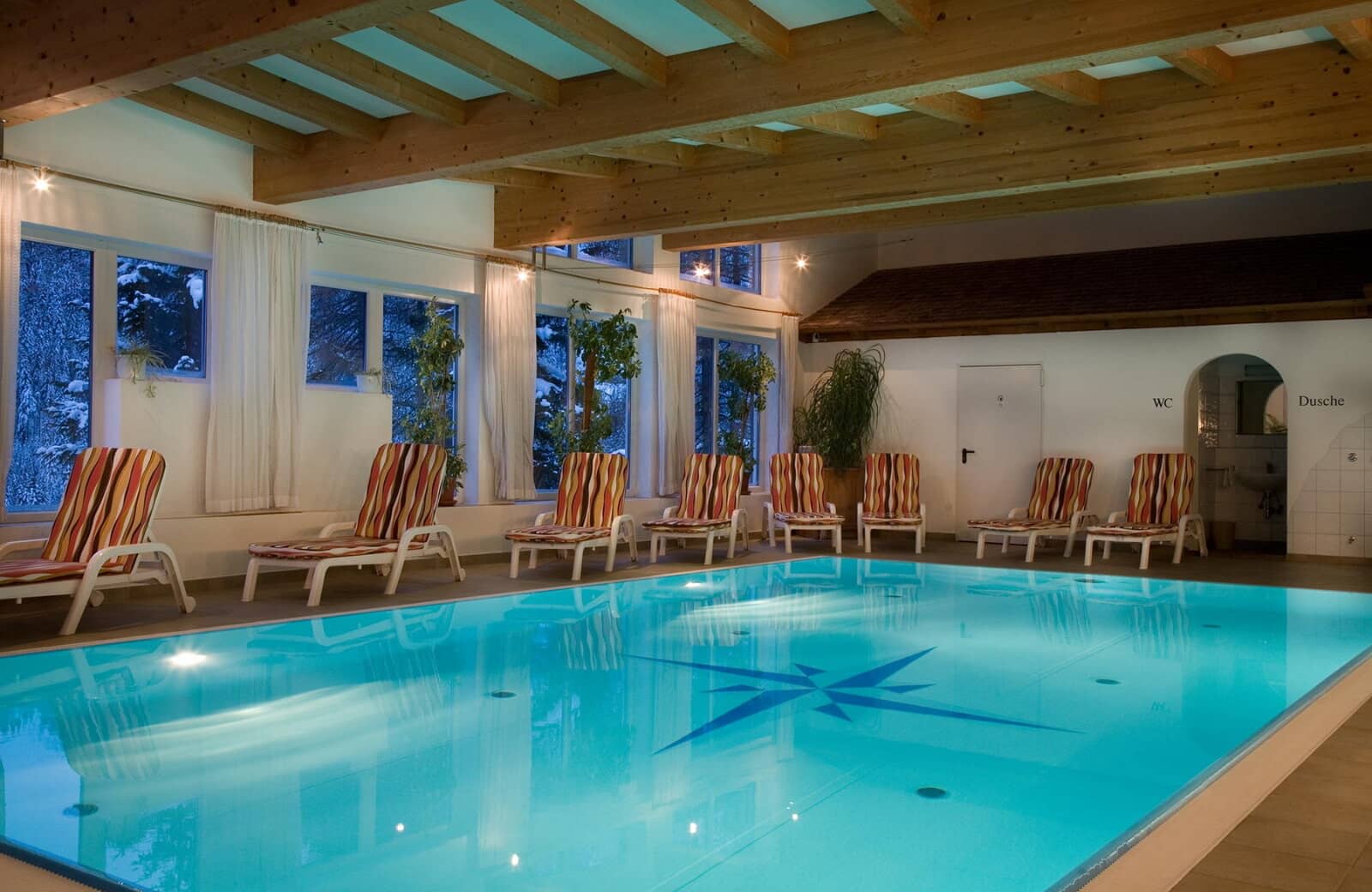 Indoor pool area with lounge seating and adjacent shower room