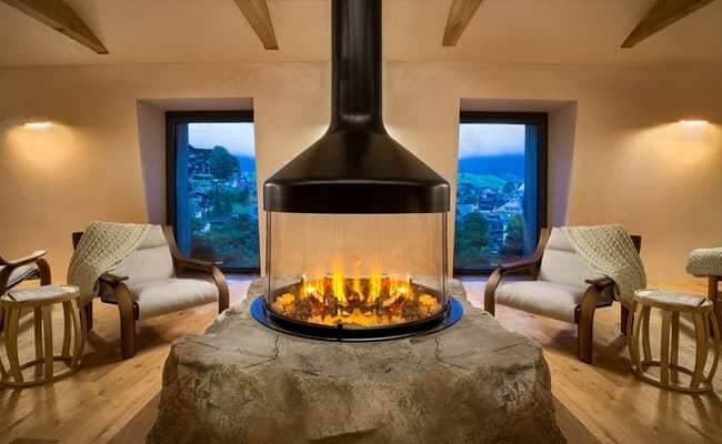 Central glass fireplace on rock base with mountain views