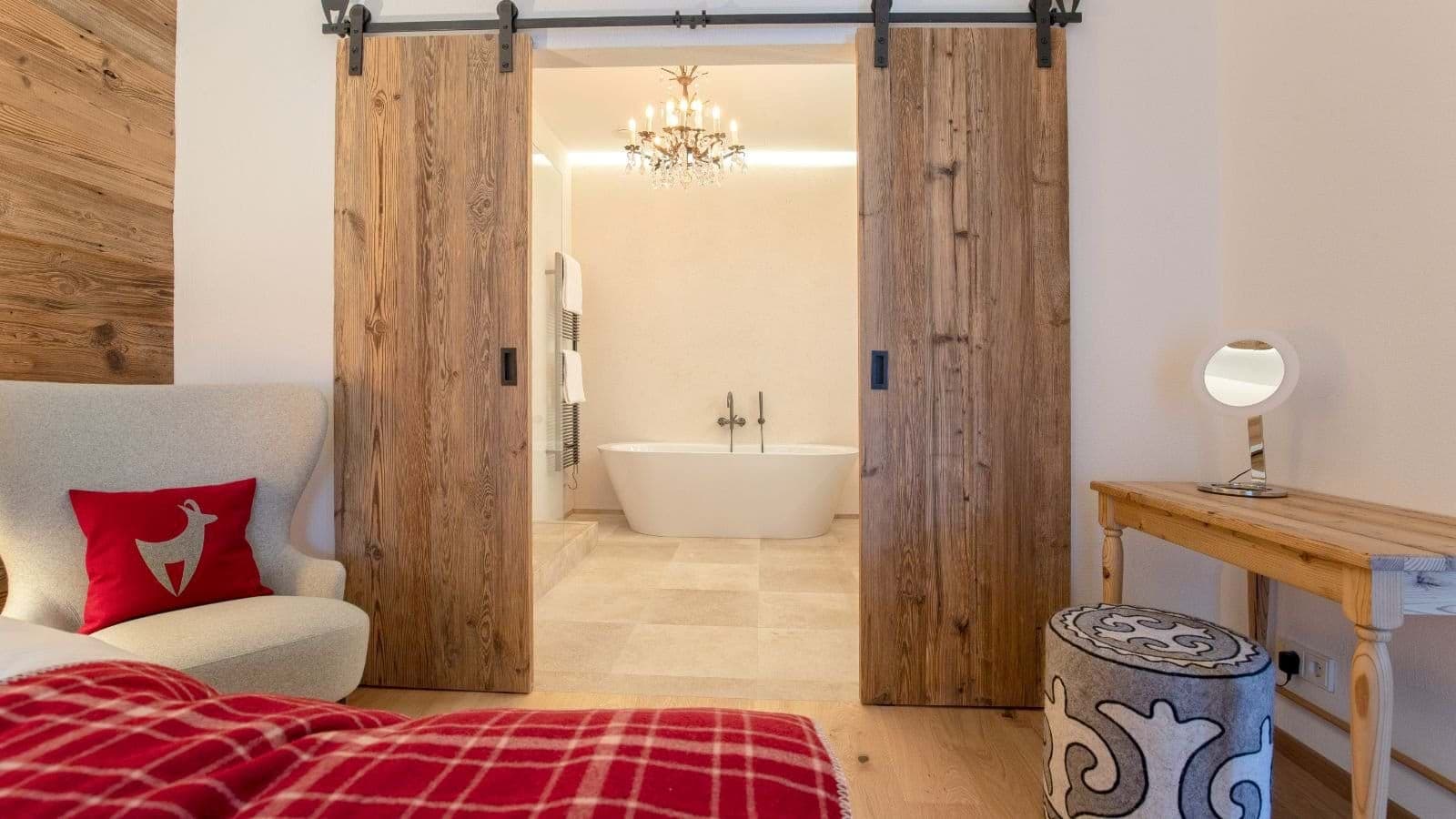 Bedroom with sliding barn doors leading to ensuite bathroom with soaking tub