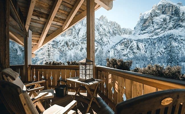Covered timber balcony with lounge seating and panoramic Dolomite mountain views