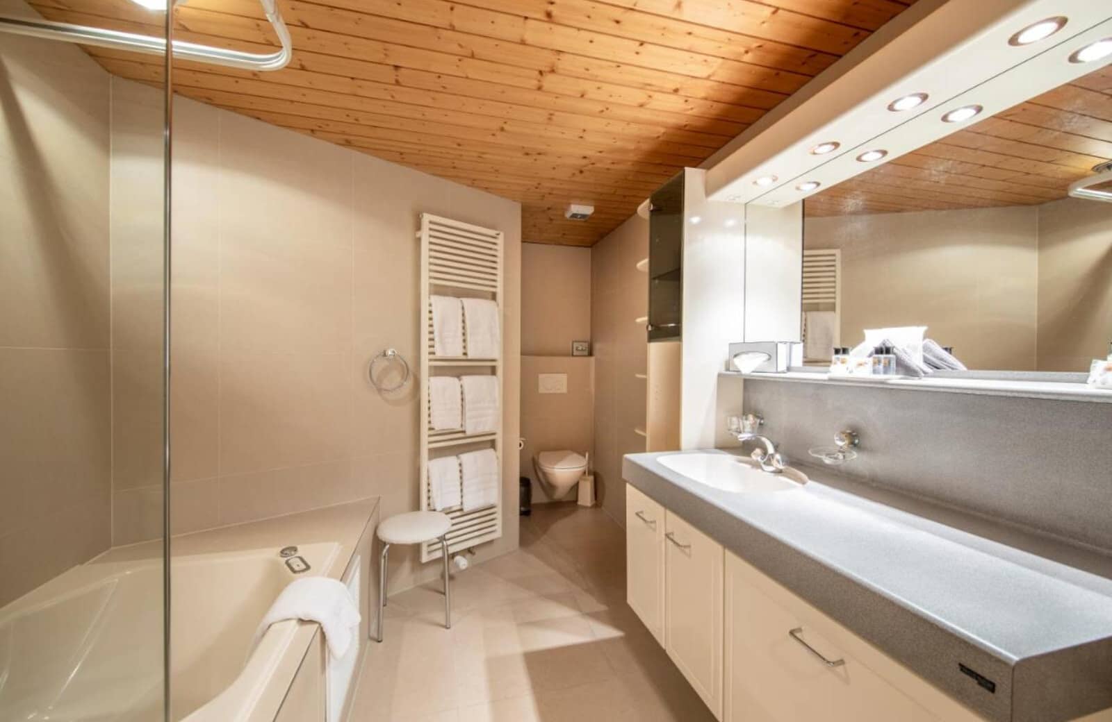 Bathroom with bathtub, heated towel rack, and wood-paneled ceiling