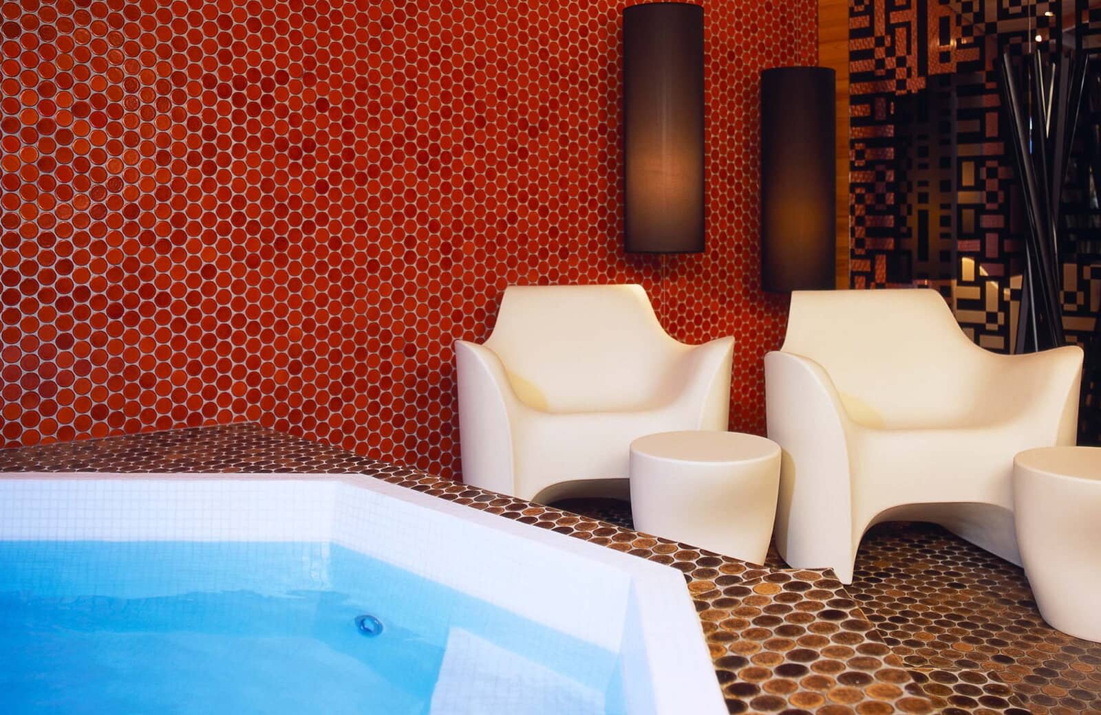 Indoor spa area with penny tile wall and poolside seating