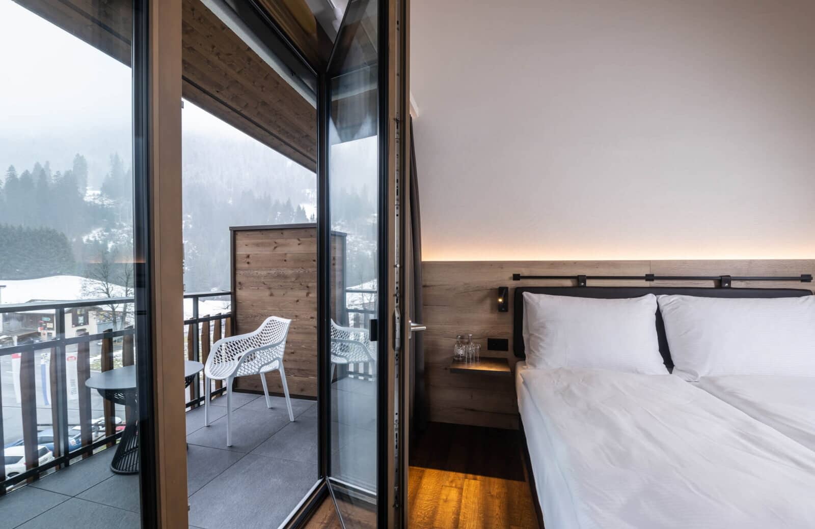 Bedroom with king bed and private balcony overlooking snow-covered mountains