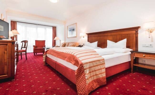 Guest bedroom with king bed, armchairs, and desk area