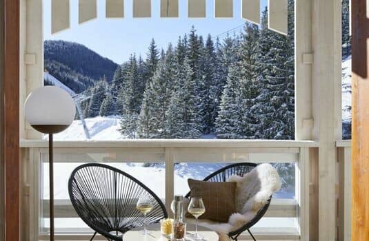 Balcony seating area with snow-covered forest and mountain valley views