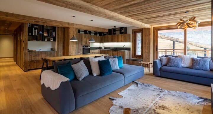Open-plan living area with dual sofas and integrated wood-paneled kitchen