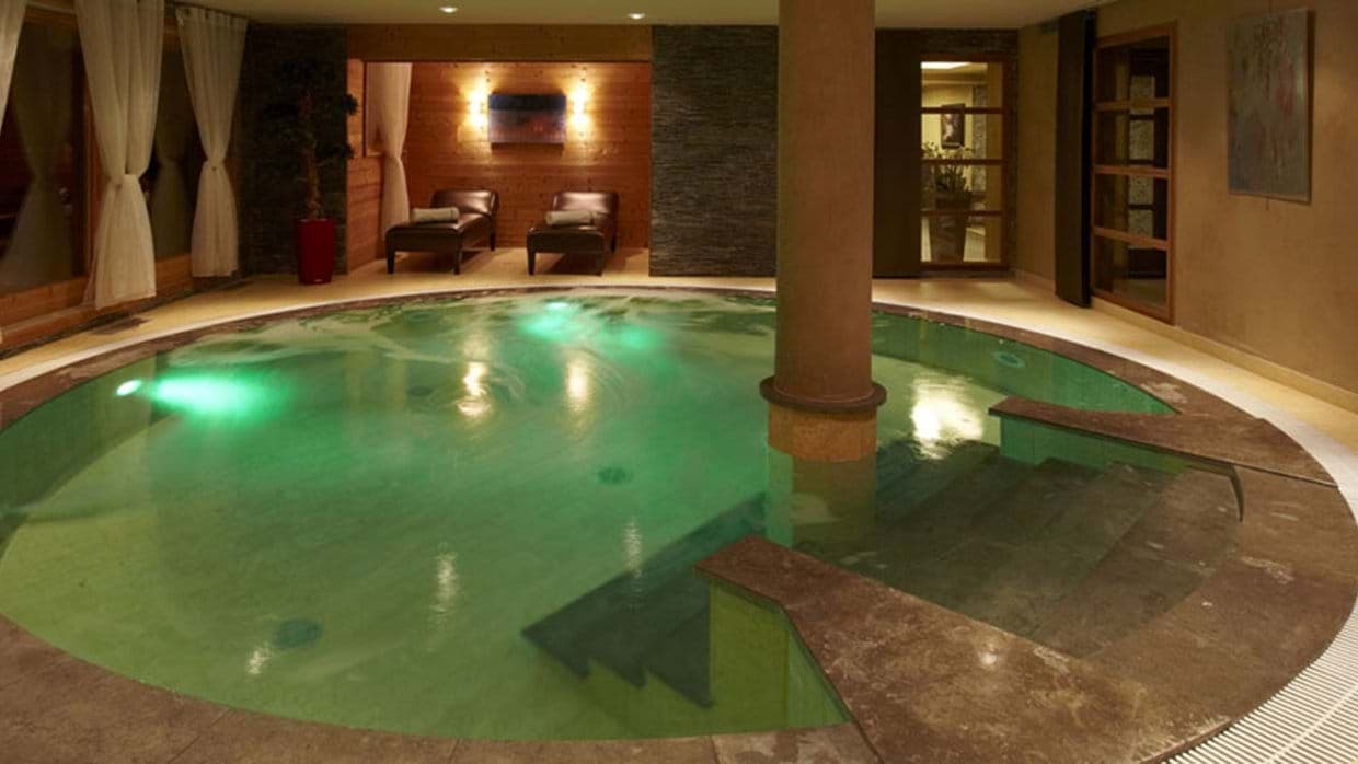 Indoor circular pool with submerged steps and poolside loungers