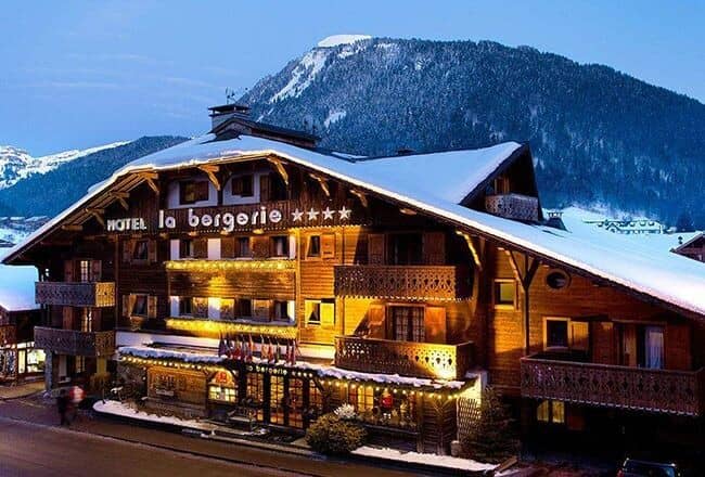 Ski-in/ski-out hotel exterior at dusk with mountain backdrop