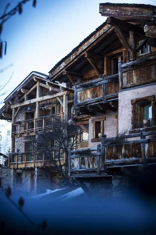 Stone and timber chalet exterior featuring private balconies and gabled rooflines