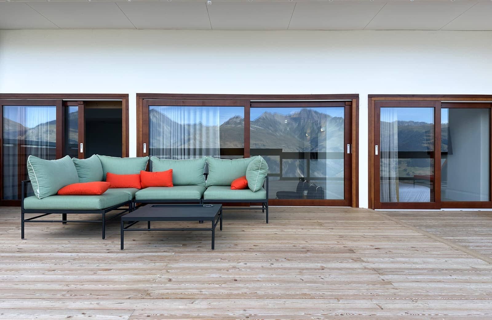 Covered timber deck with sectional seating and mountain reflections