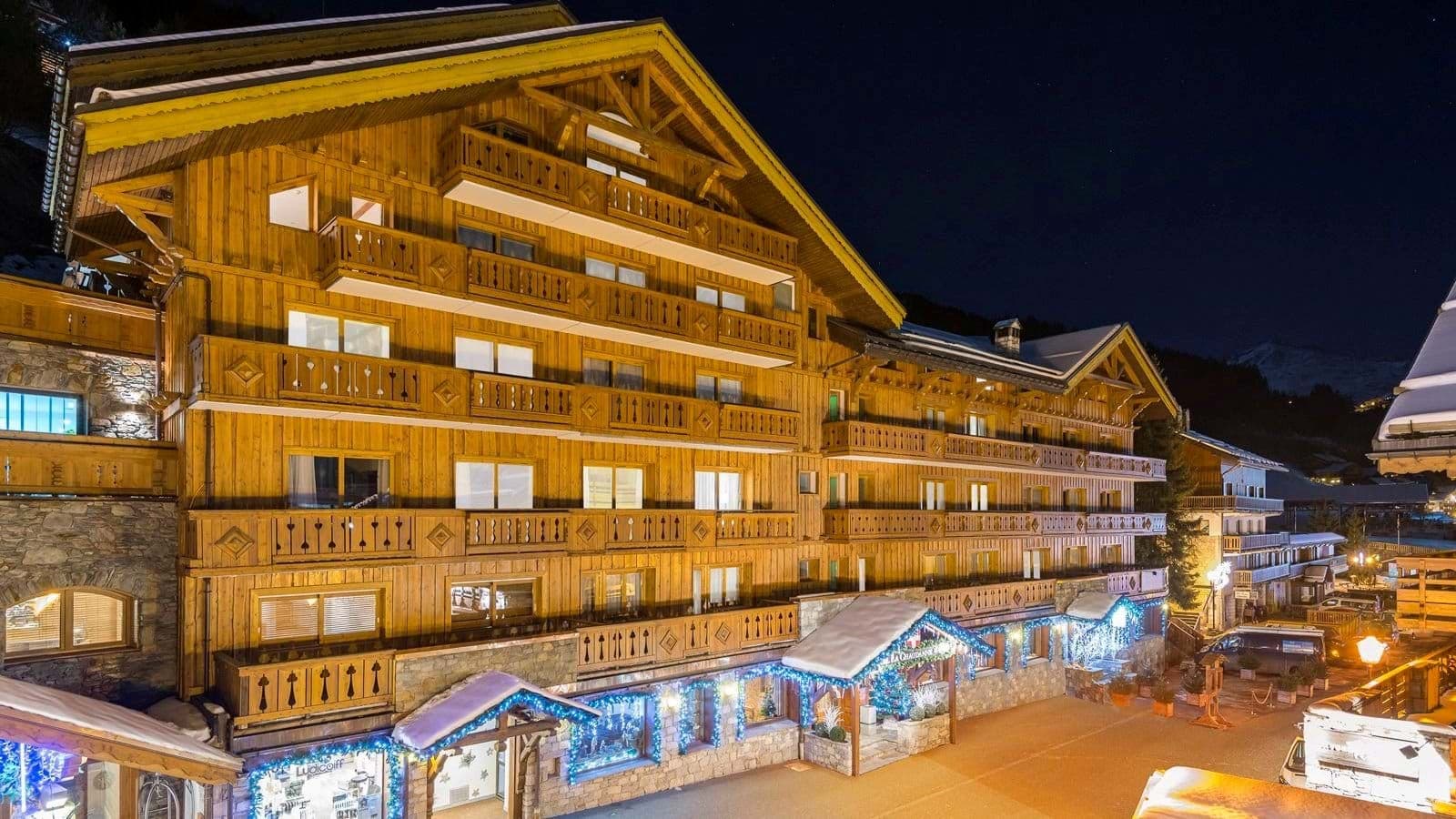Chalet exterior with multiple private balconies and illuminated street-level entrance
