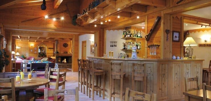 Private bar area with stool seating; pool table and fireplace beyond