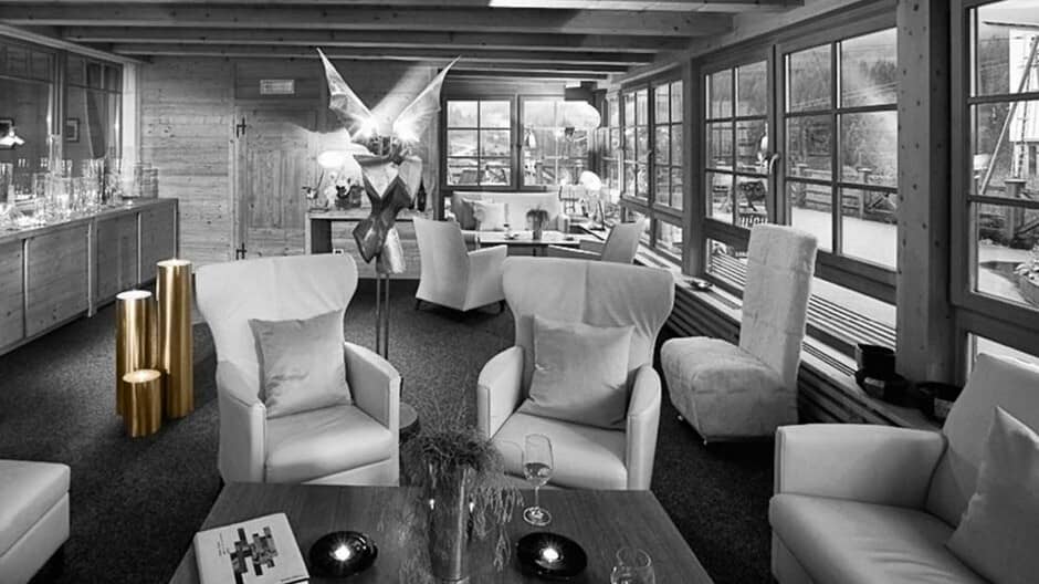 Lounge area with armchair seating and floor-to-ceiling windows overlooking the slopes