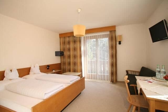 Guest bedroom with twin beds, private balcony, and wall-mounted TV