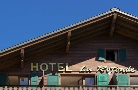Chalet-style exterior featuring Hotel La Rotonde signage and traditional wooden shutters