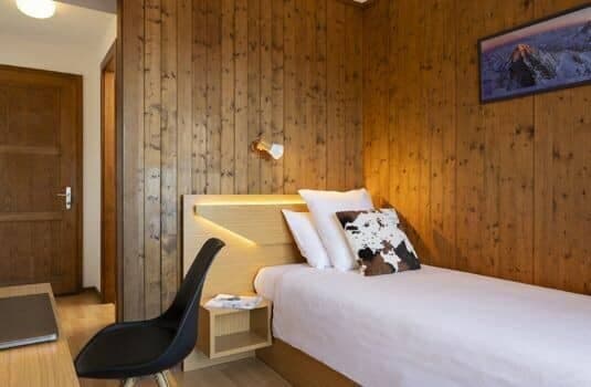 Guest bedroom with single bed, wood-paneled walls, and integrated desk