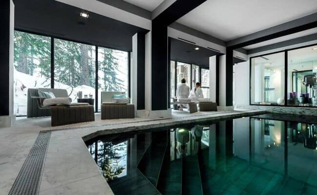 Indoor pool and spa area with floor-to-ceiling forest views