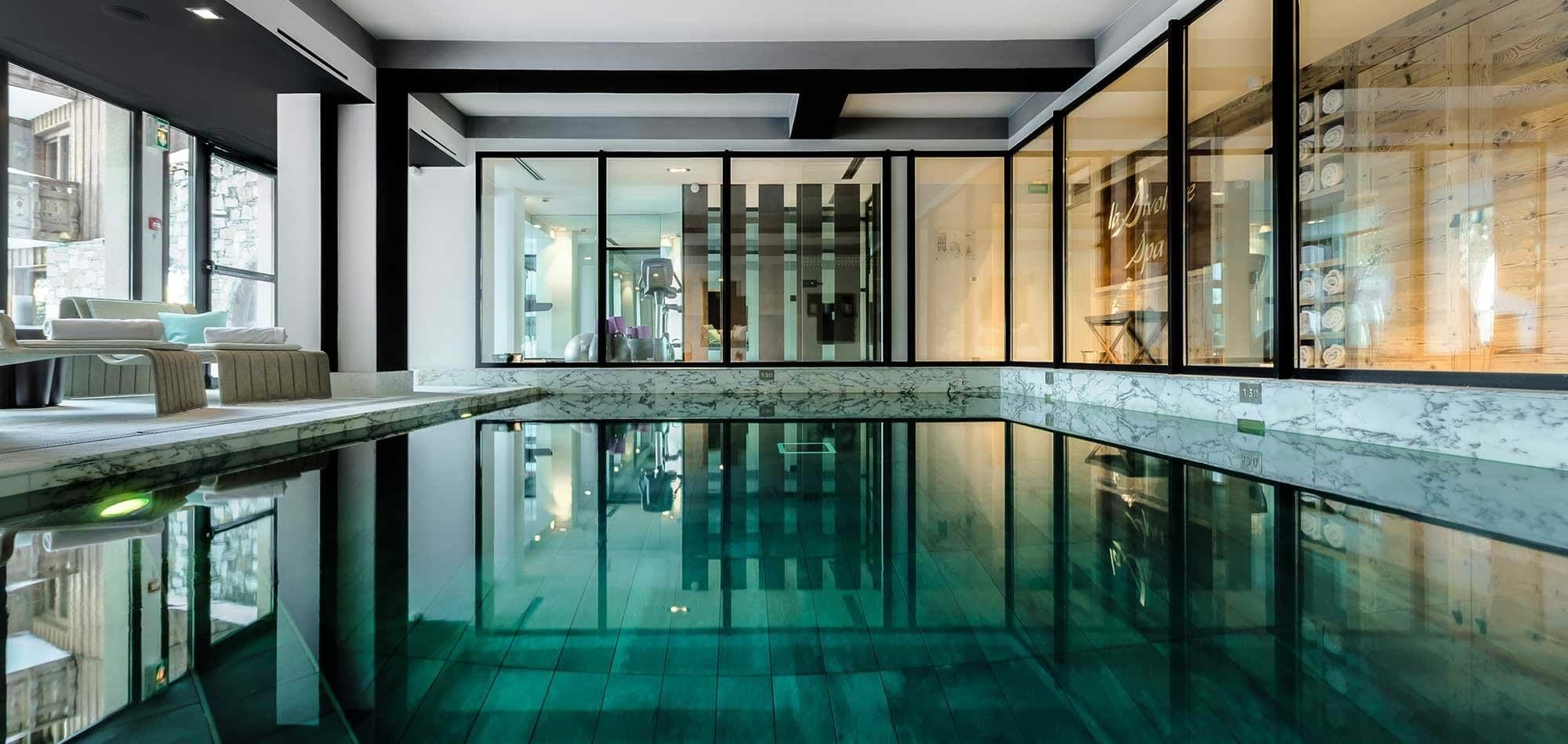 Indoor pool with marble trim and view of fitness center