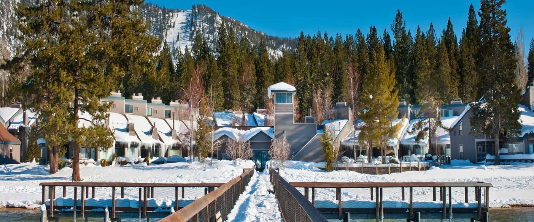 Lakeside complex with pier and views of mountain ski slopes
