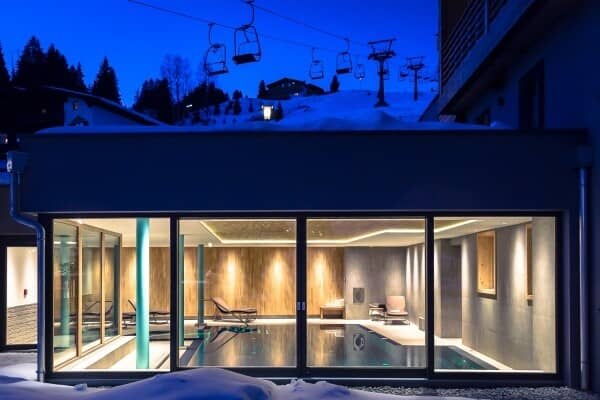 Indoor heated pool with floor-to-ceiling windows and ski lift views
