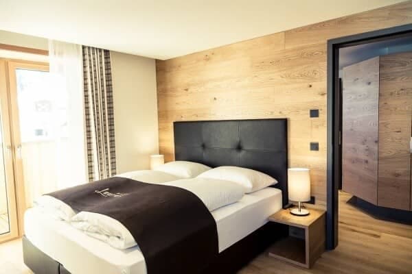 Primary bedroom with king bed, reclaimed wood walls, and balcony access