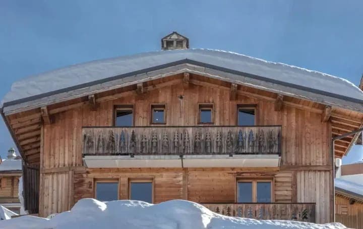 Timber chalet facade with upper-level balcony and decorative pine tree carvings