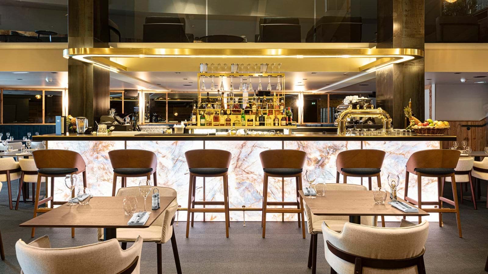 Hotel bar with backlit stone counter and seating for six