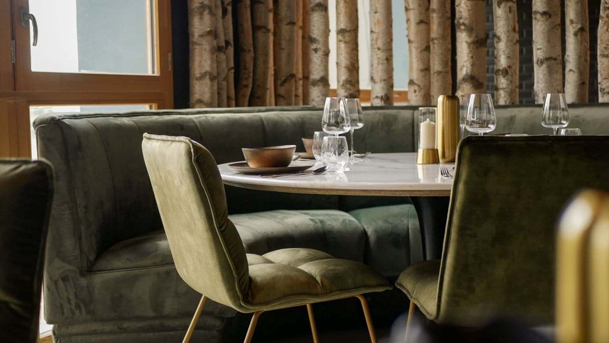 Dining area with round marble table and velvet banquette seating