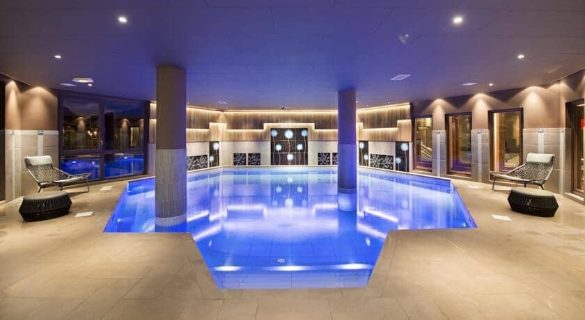 Indoor heated pool with integrated lounge seating and atmospheric lighting