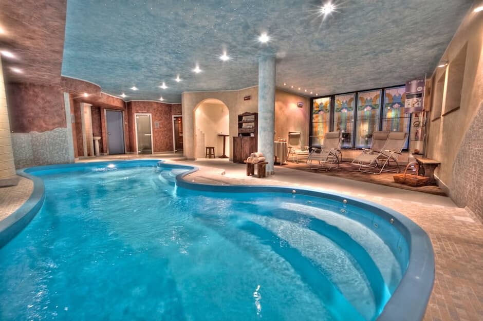 Indoor pool and hot tub with lounge seating; heated ceiling