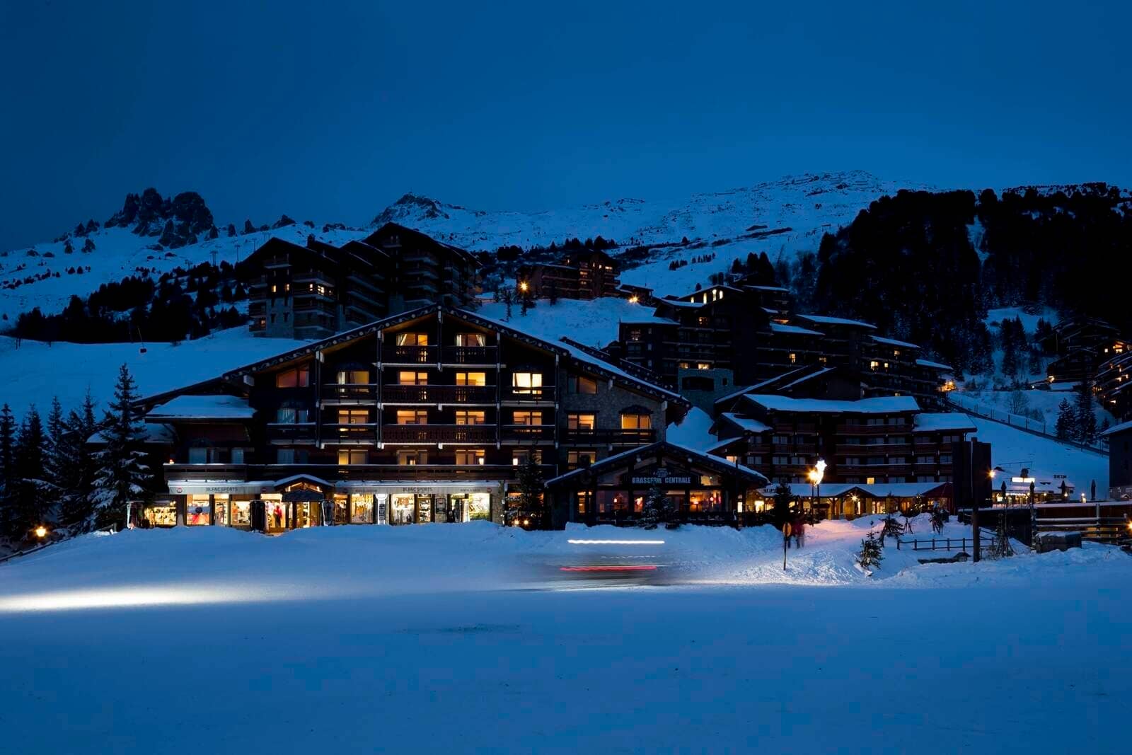 Ski-in/ski-out chalet exterior with illuminated village and mountain views at dusk