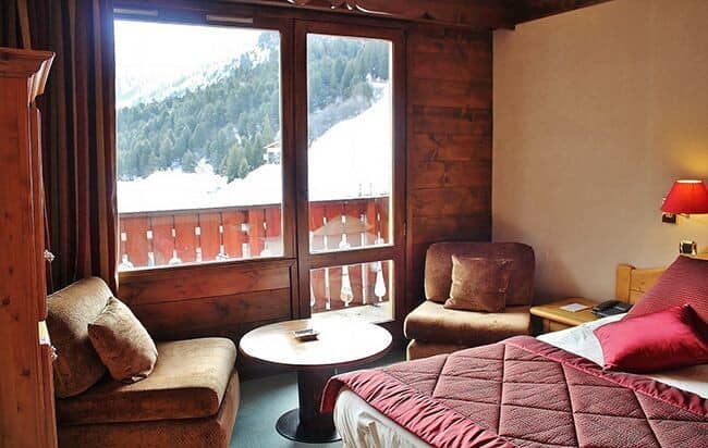 Bedroom seating area with balcony and snow-capped mountain views