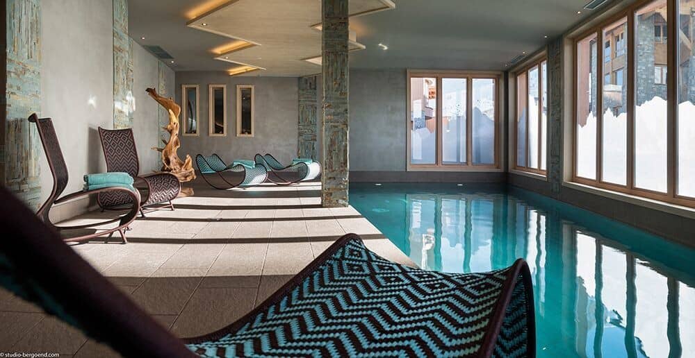 Indoor heated pool with lounge seating and mountain-view windows