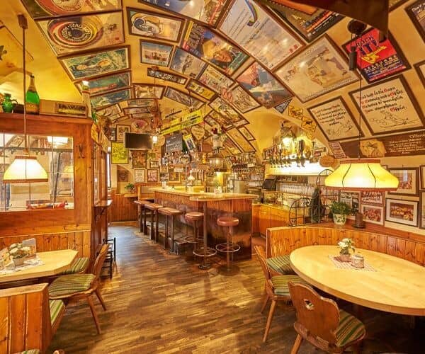 Lower level tavern with barrel-vaulted ceiling, bar seating, and booth tables