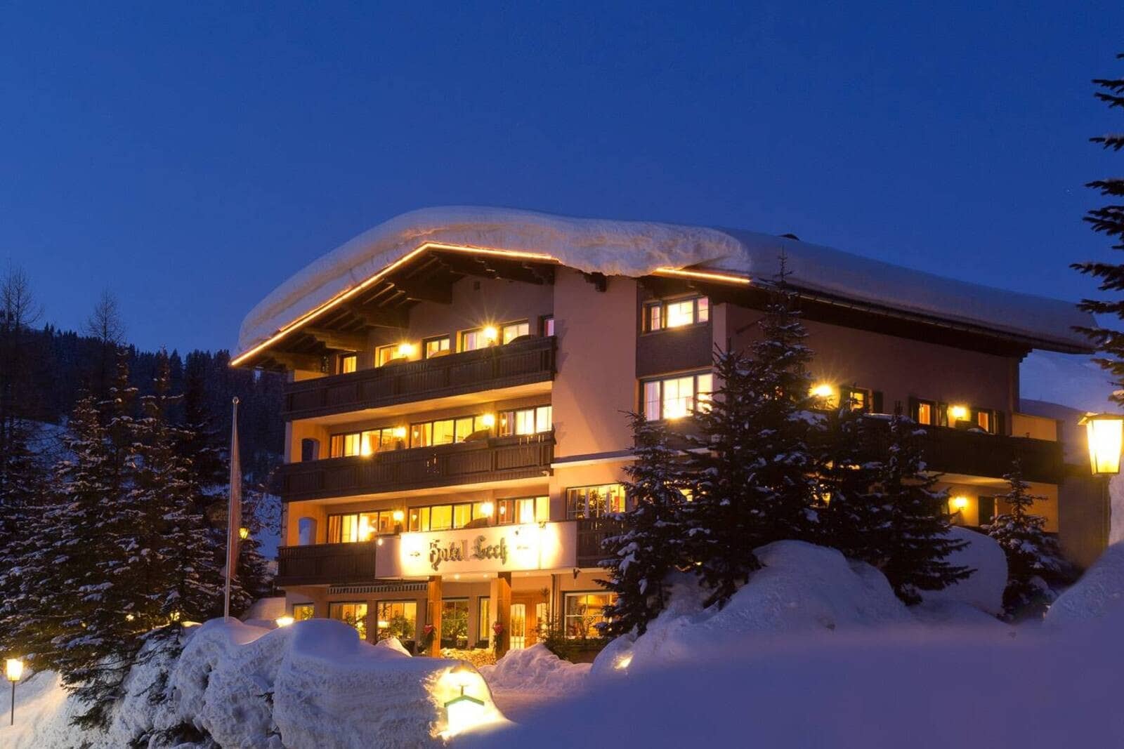 Ski chalet exterior with illuminated private balconies and snow-covered grounds