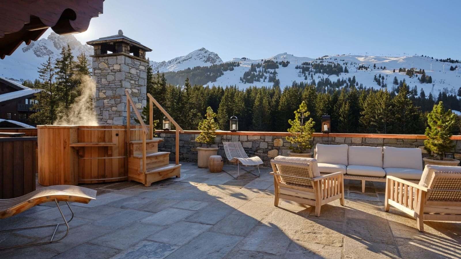 Stone terrace with cedar hot tub and lounge seating; panoramic mountain views