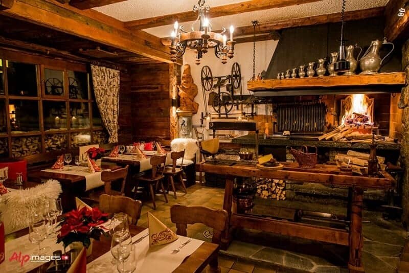 Dining area with wood-burning rotisserie fireplace and rustic timber beams
