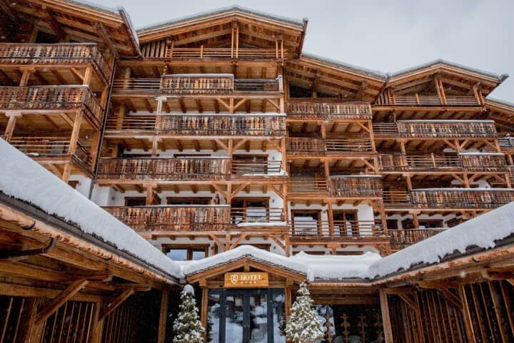Timber chalet exterior featuring private balconies and snow-covered gabled roofs